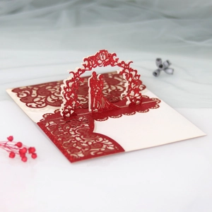 Detail of 3D laser cut wedding invitation showing a glittery red floral arch and couple