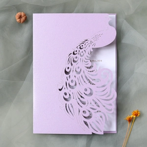 Close-up of laser-cut peacock wedding invitation with glitter lavender finish