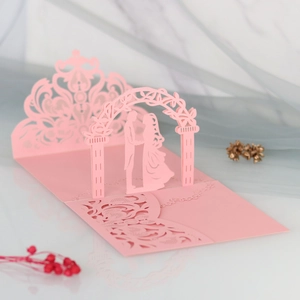 Detailed laser-cut pink 3D wedding card showing a couple under an ornate floral arch