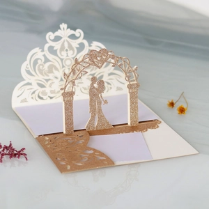 Macro view of 3D pop-up wedding card with rose gold glitter couple and laser-cut details