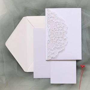 Macro view of white laser-cut floral wedding invitation set with envelopes and cards