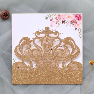 Macro view of laser-cut gold glitter wedding invitation with floral inner card details