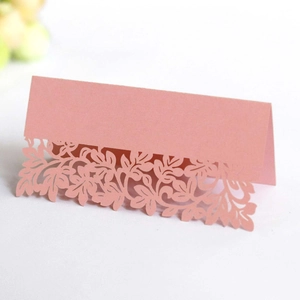 Macro detail of laser-cut floral wedding place card in pearlescent soft pink paper