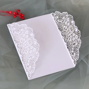 Détail d'invitation de mariage blanche découpée au laser avec motifs de fleurs et papillons