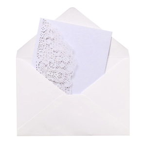 Detail of white laser-cut wedding invitation with elegant hollow patterns and envelope