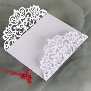 Macro shot of laser-cut white wedding invitation with elegant baroque floral cutout detail