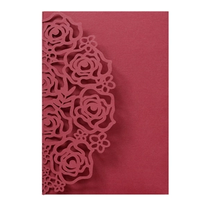 Detail of laser-cut rose patterns on deep red wedding invitation card paper