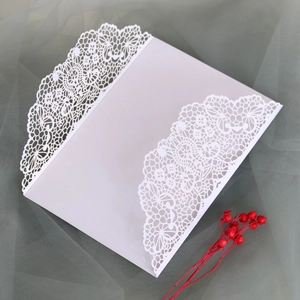Détail macro du faire-part de mariage en dentelle découpée avec fleurs séchées rouges