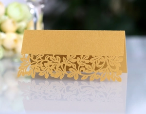 Detail view of laser-cut gold pearlescent paper place card with elegant leaf patterns