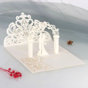 Close-up of laser cut 3D wedding invitation featuring a bride and groom under a floral arch