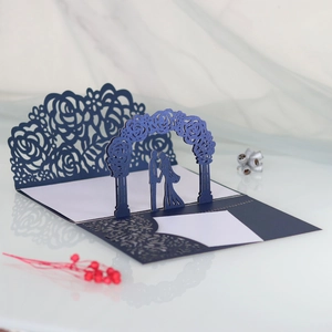 Macro detail of laser-cut 3D wedding card with bride and groom under a rose arch
