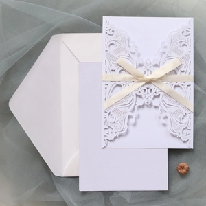 Detailed laser-cut wedding invitation set with lace pattern, inner card, and satin ribbon