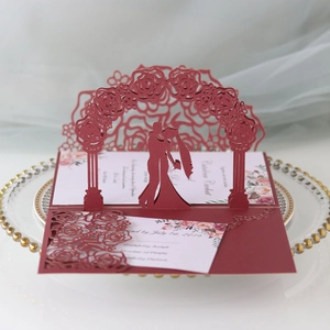 Detail of laser-cut burgundy wedding card with rose arch and couple silhouette