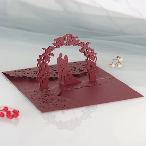 Dettaglio del biglietto nuziale 3D con coppia tagliata al laser sotto un arco fiorito
