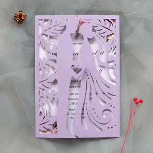 Detail of laser-cut wedding invitation in light purple with bride and groom silhouette