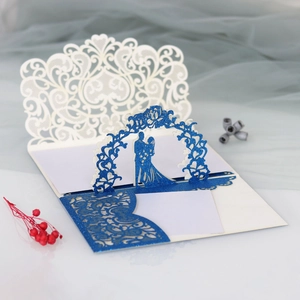 Detailed laser-cut wedding invitation featuring white lace patterns and blue glitter accents