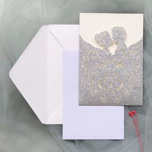 Detail of laser-cut silver glitter wedding invitation with bride and groom silhouette