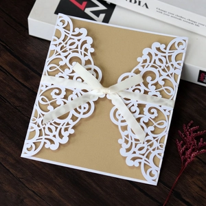 Detail of laser cut wedding invitation featuring golden glitter paper and silk bow decor