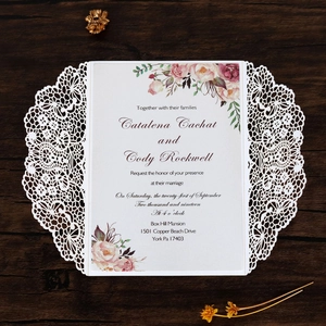 Vue macro de l'invitation de mariage en dentelle découpée au laser et fleurs aquarelle