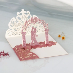 Close-up of 3D laser-cut wedding invitation featuring pink glitter arch and silhouettes