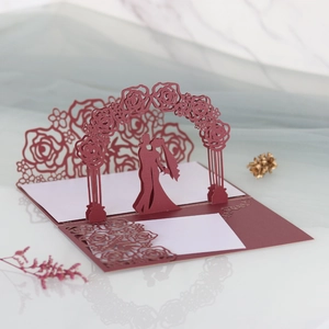 Macro view of 3D laser cut wedding card with rose arch and couple in dark red