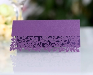 Macro shot of purple laser-cut place cards with elegant pearl finish and floral details