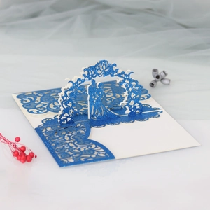 Macro detail of laser-cut 3D wedding card with couple under a blue glitter archway