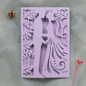 Intricate laser-cut lavender wedding invitation featuring silhouettes of a kissing couple