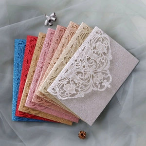 Close-up of laser-cut glitter paper wedding invitations in assorted metallic colors