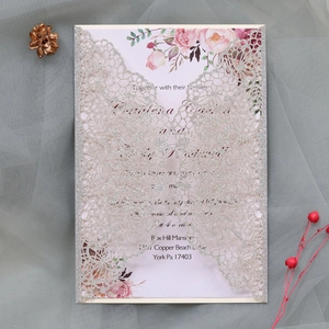 Macro detail of silver glitter laser cut wedding invitation with hollow butterfly pattern