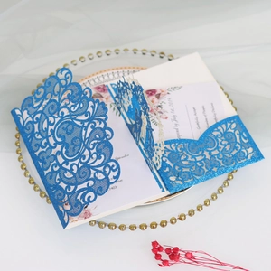 Detail of laser-cut glitter blue invitation with elegant floral card insert and envelope