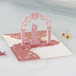 Close-up of laser-cut 3D wedding invitation with pink glitter card and couple design