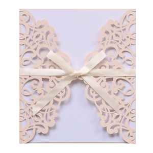 Elegant laser cut pink wedding invitation with intricate floral patterns and a silk bow