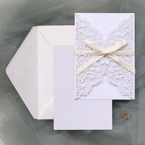 Détail d'invitation de mariage découpée au laser avec nœud papillon et encart sur filet