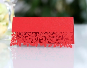 Detailed close-up of laser-cut leaf patterns on a red pearl paper wedding table card