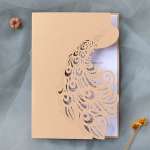 Close-up of laser-cut peacock wedding invitation with golden hollow patterns and pearl paper