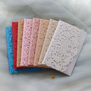 Macro detail of multi-color glitter laser-cut floral wedding invitations and envelopes