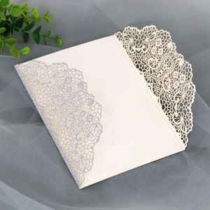 Close-up of laser-cut wedding invitation with elegant lace pattern and silver glitter finish