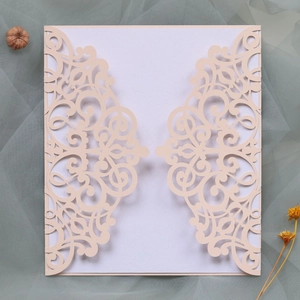Detail of laser-cut light pink wedding invitation with elegant scroll patterns