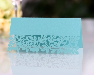 Detailed laser-cut floral pattern on light blue pearlescent paper wedding table card