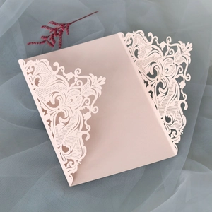 Close-up of laser-cut lace patterns on dusty pink wedding invitation envelope