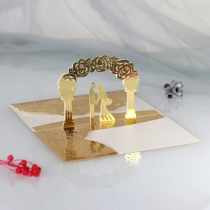 Detail of 3D laser-cut wedding card featuring a golden rose arch and couple silhouette