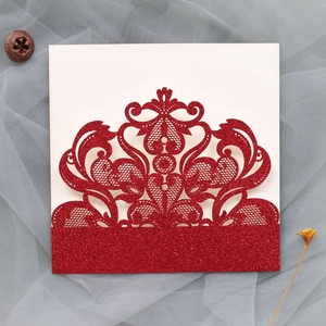 Close-up of red glitter laser-cut lace wedding invitation cover with floral patterns