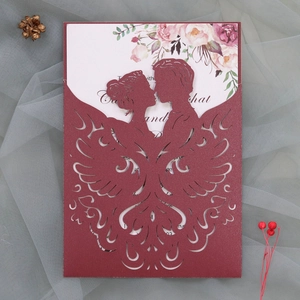 Close-up of laser-cut burgundy wedding invitation with silhouette and floral inner card