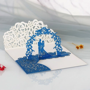 Détail d'une carte de mariage 3D avec silhouette bleue pailletée et roses découpées laser