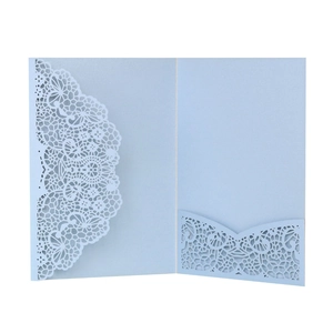 Detail view of light blue laser-cut wedding invitation with intricate lace floral patterns