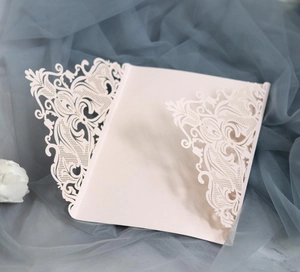 Detail of laser-cut lace pattern on pink wedding invitation with floral hollow design