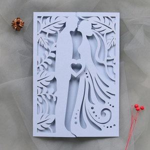 Close-up of laser-cut wedding invitation featuring a romantic bride and groom silhouette