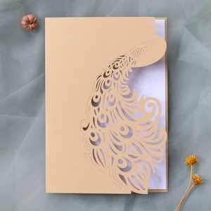 Macro detail of laser cut champagne gold peacock wedding invitation with intricate hollow pattern