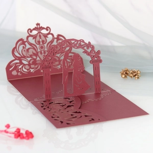 Macro view of burgundy laser-cut 3D wedding invitation with couple silhouette